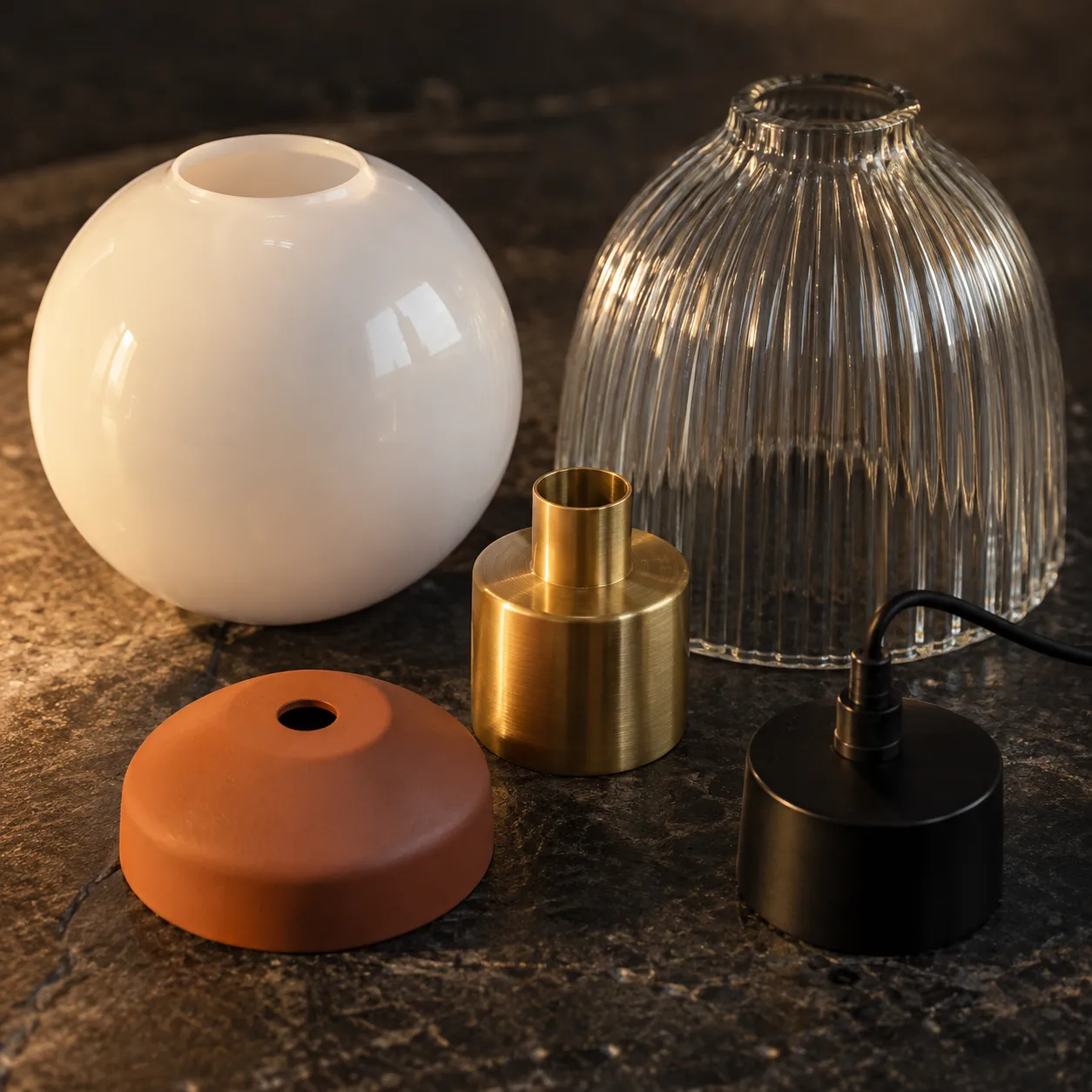 Glass, brass, terracotta, and aluminum lighting materials arranged for inspection